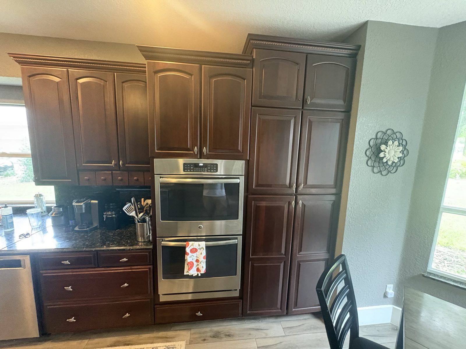 Before: dark cherry cabinets around the double wall ovens